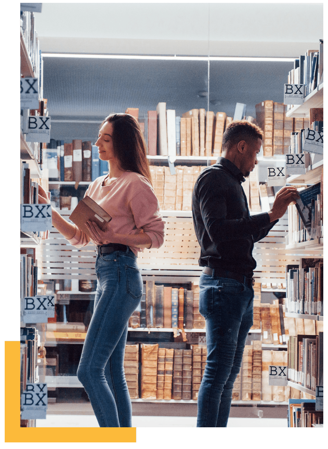 A female and male student in the library searching for a book